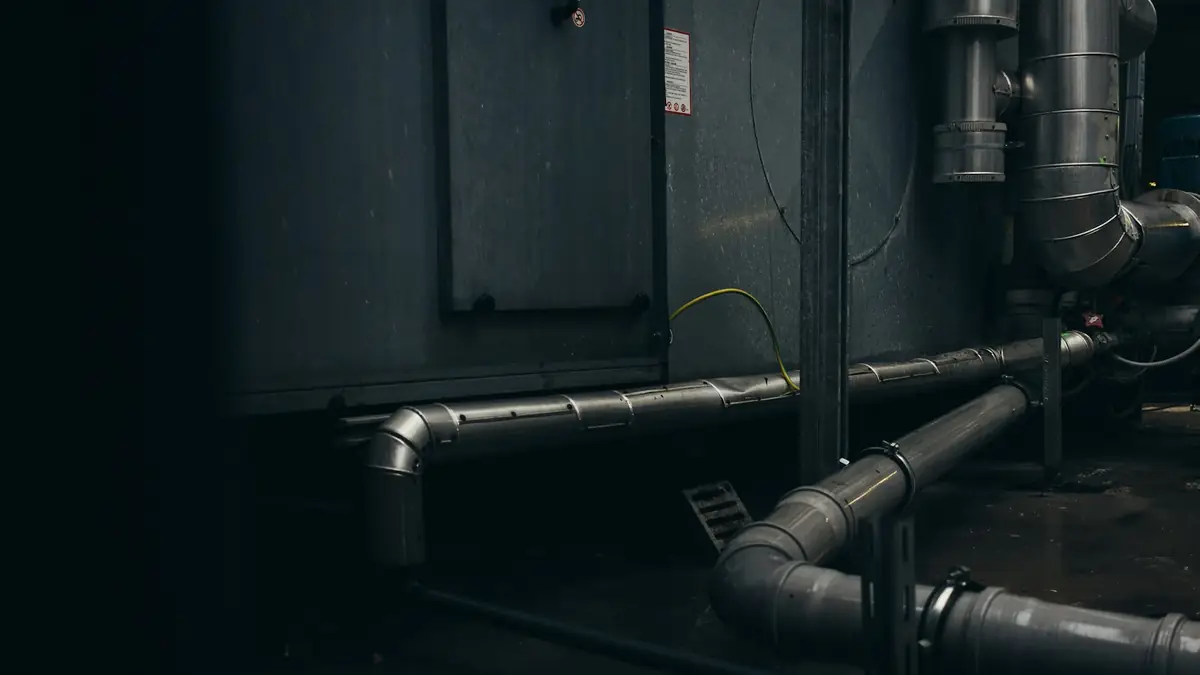 A dark mechanical room with drain pipes running along the wall - Leak Detection in Mount Prospect
