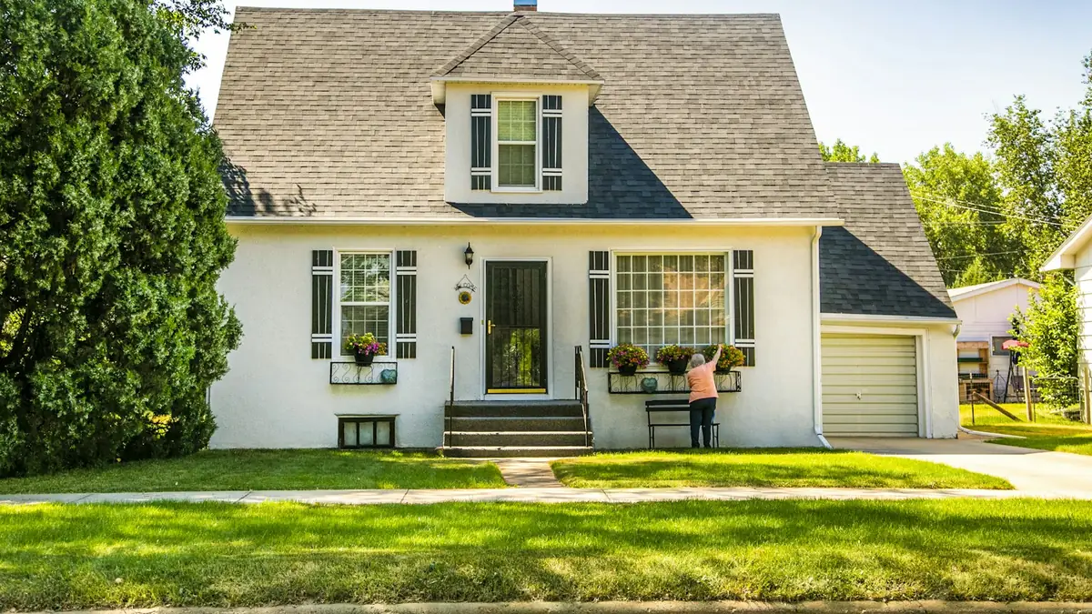 A white cottage-style house with dormers and a green lawn - Leak Detection in Mount Prospect
